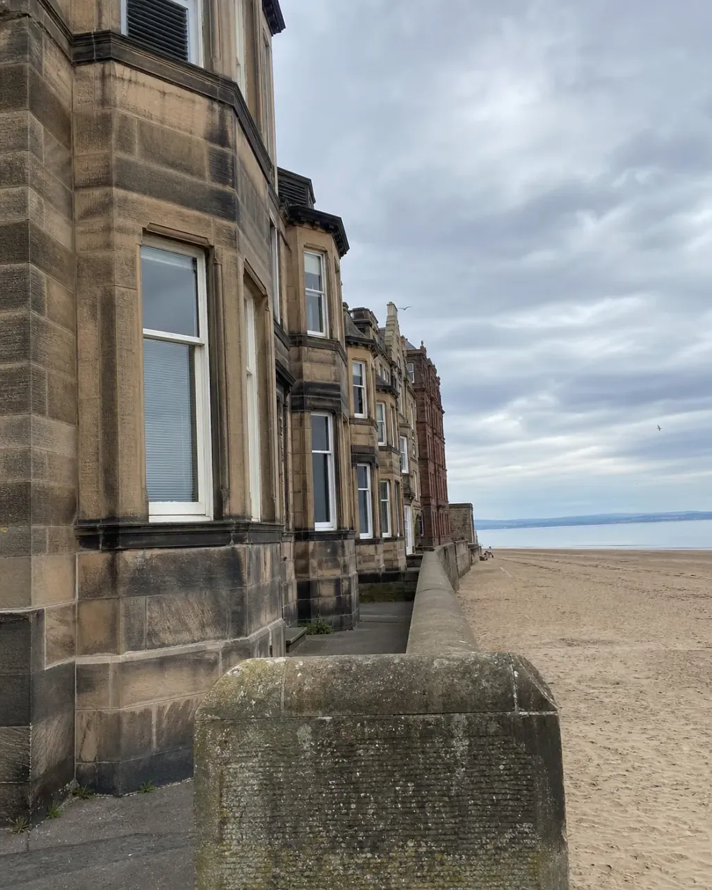 Bay-windowed stone terraces beside the sea wall and beach at Portobello