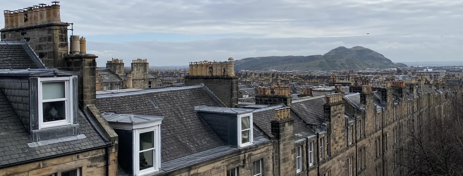 Slate tenement rooftops and chimney stacks looking toward Arthur's Seat